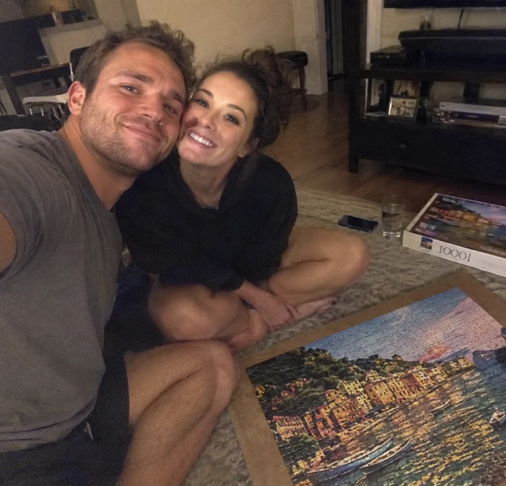A couple smiling beside the seaside puzzle they completed together